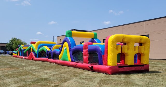 A long, colorful inflatable obstacle course set up on a grassy field